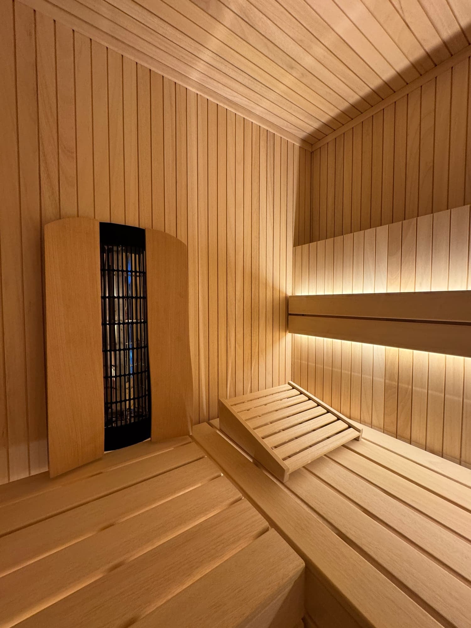 The interior of a wooden Sauna with benches and a heater.